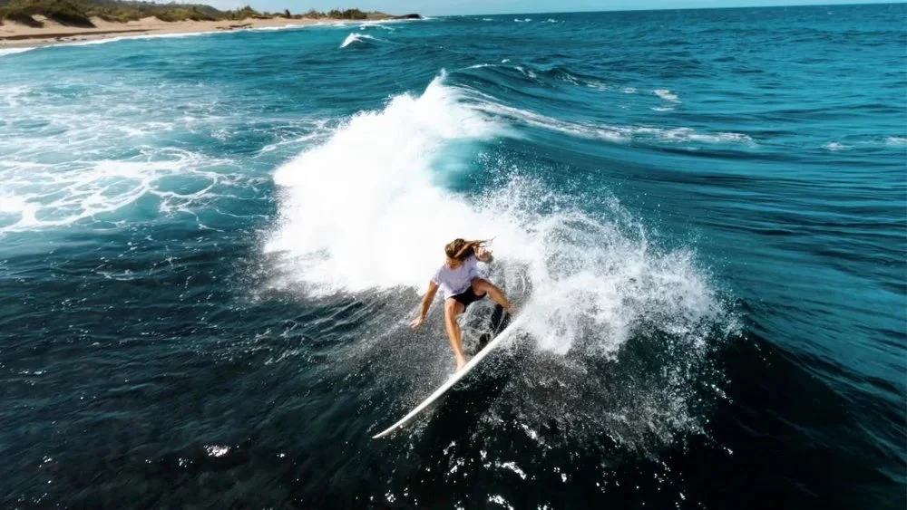 Surfer carving across a bright blue wave